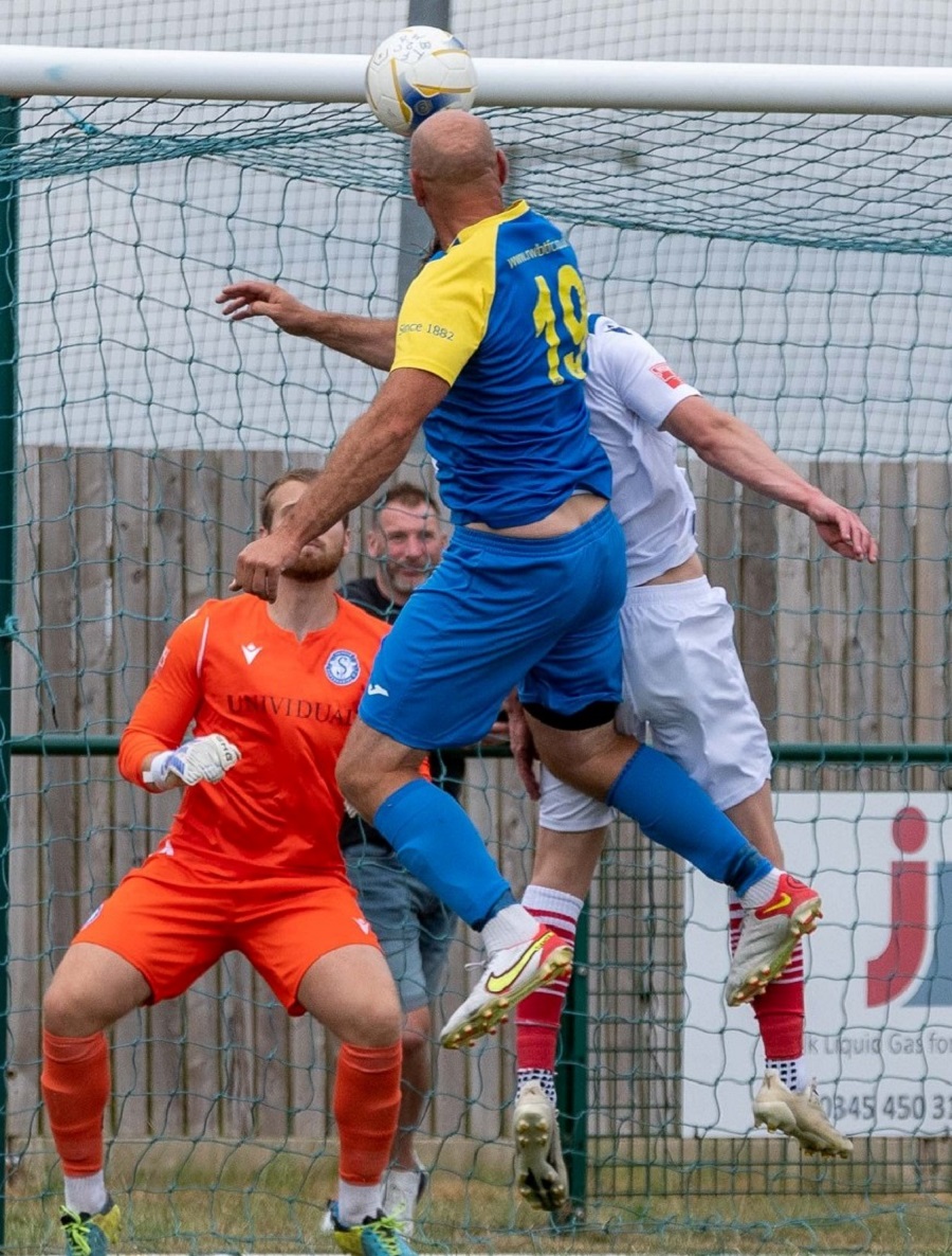 Bassett’s Alan Griffin gets above Jack Stanley to head home a trademark goal